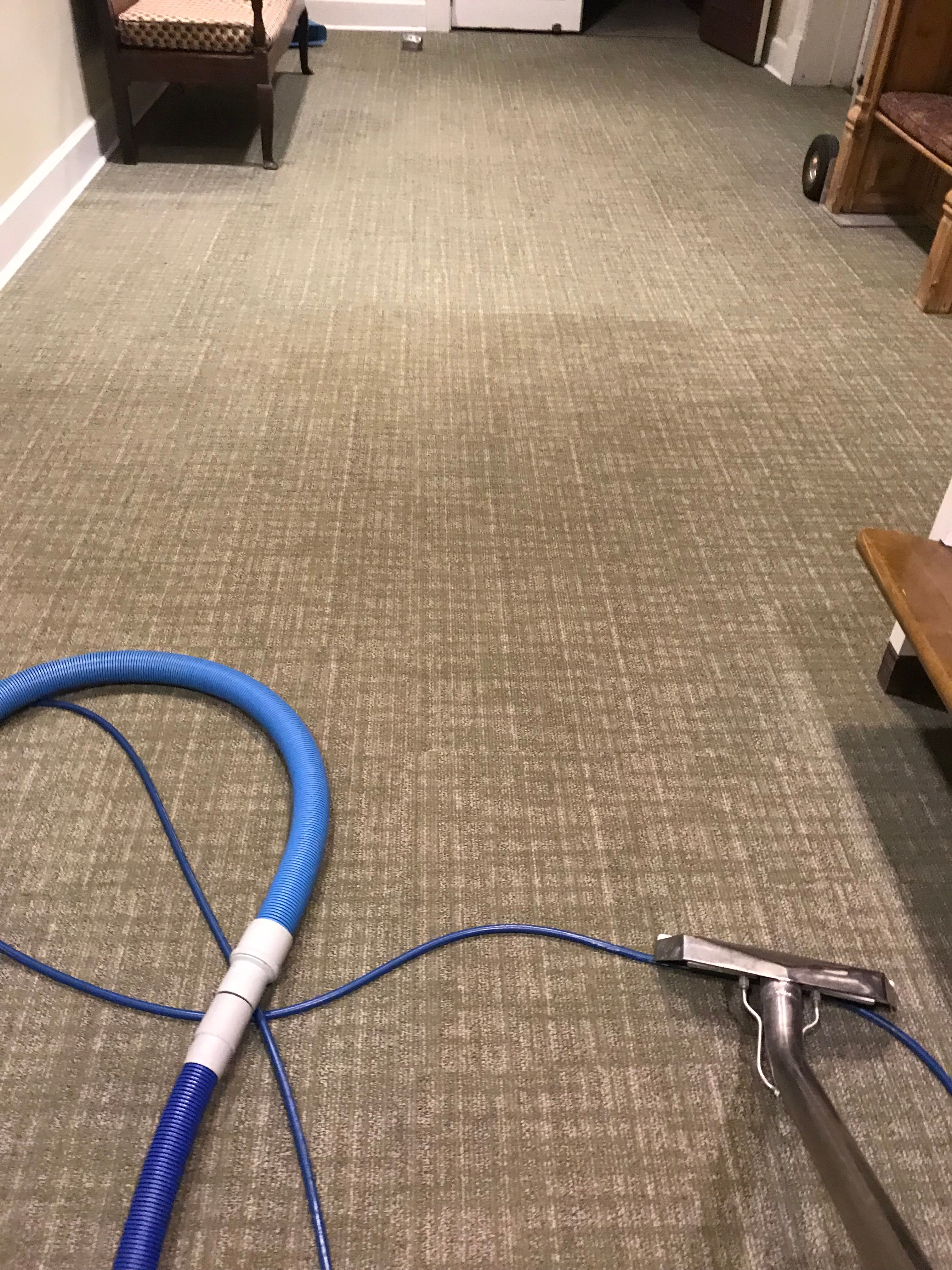 Commercial hallway carpet being cleaned with a wand and hose
